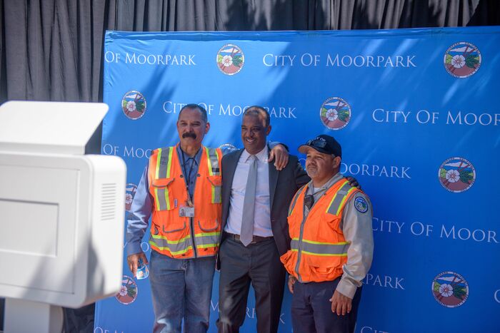 Three men posing in front of a City of Moorpark banner