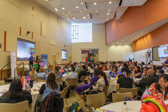 Wide view of a full conference hall with attendees seated at round tables