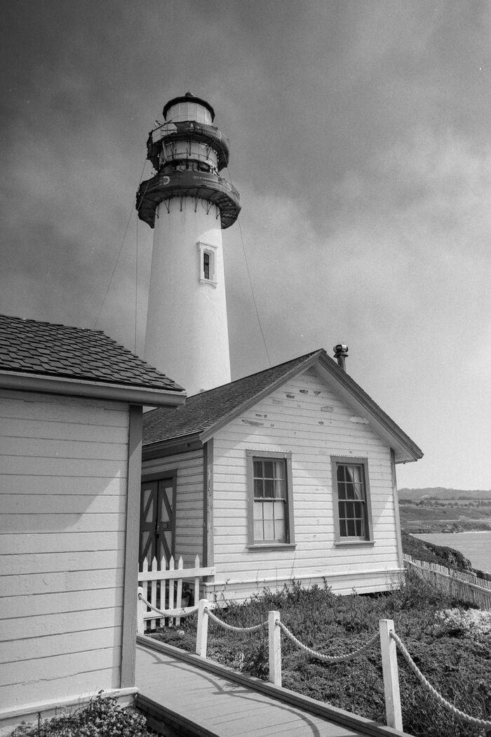 White lighthouse and cottage under a stormy sky, black and white