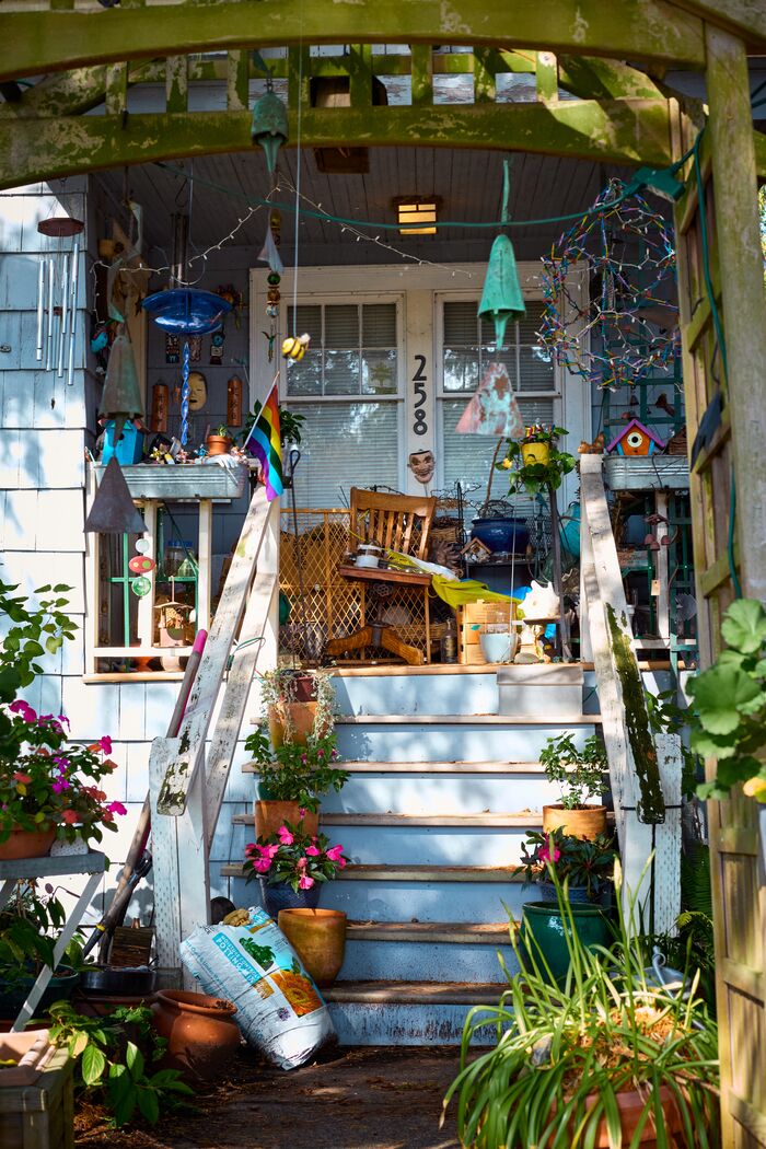 Colorful porch crowded with plants, wind chimes, and trinkets