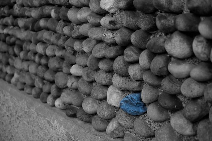 Wall of rounded grey stones with a single blue stone