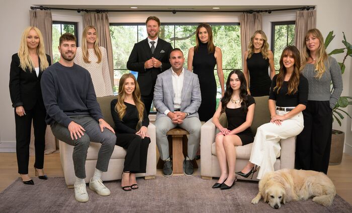 Full team portrait of eleven people and a golden retriever in a bright living room